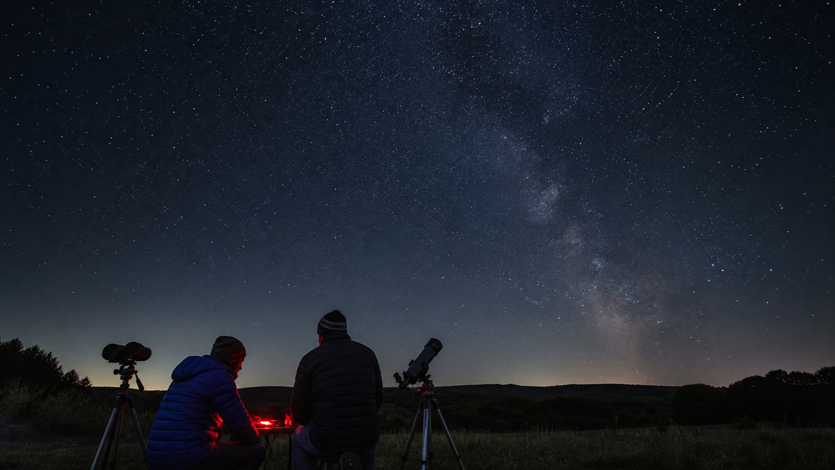 Two amateur skywatchers setting up telescopes under a clear early-autumn star field