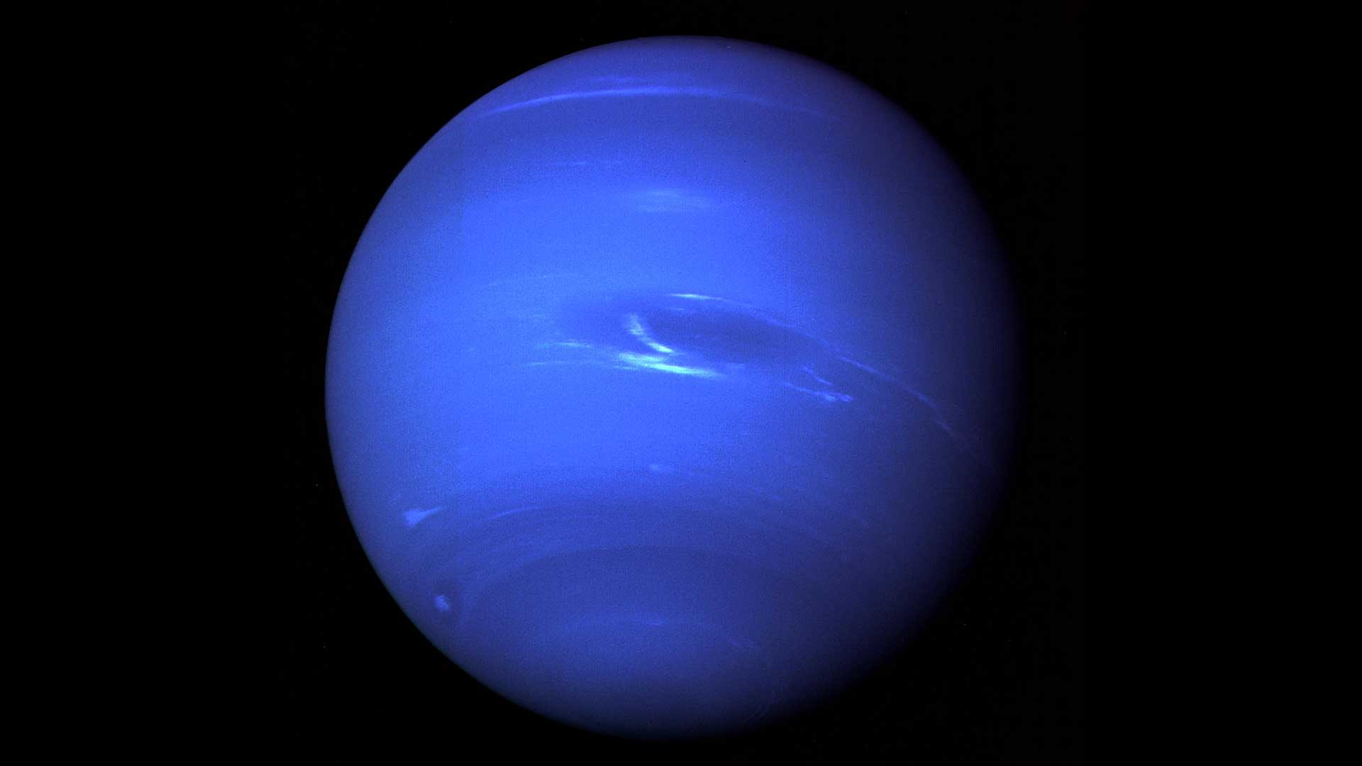 Voyager 2 full-disk view of blue Neptune with visible atmospheric bands and storms